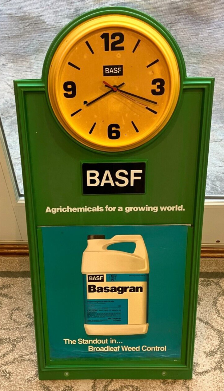 Antique yellow  clock on a BASF sign advertising Basagran.