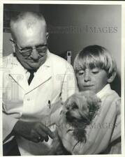 1969 Press Photo Veterinarian gives dog held by boy a rabies vaccination picture