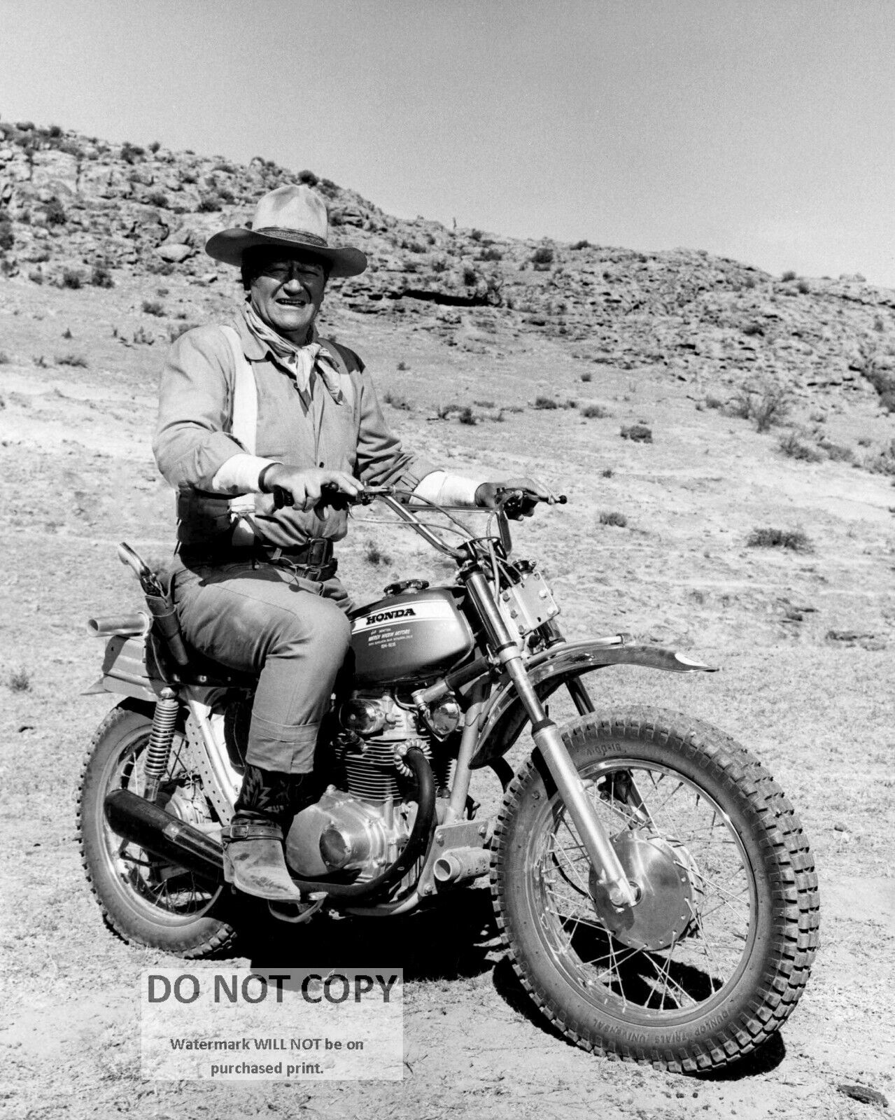 JOHN WAYNE RIDES HONDA MOTORCYCLE ON THE SET OF 